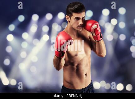 Giovane uomo con guanti da boxe e faretti sullo sfondo Foto Stock