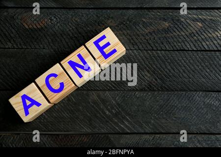 ACNE di parola dei cubi su sfondo di legno. Concetto di cura della pelle Foto Stock