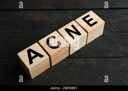 ACNE di parola dei cubi su sfondo di legno. Concetto di cura della pelle Foto Stock