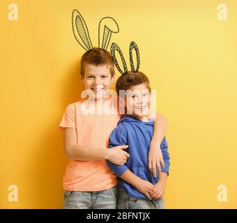 Bambini carini con orecchie di coniglietto disegnate su sfondo colorato Foto Stock