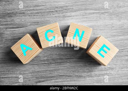 ACNE di parola dei cubi su sfondo di legno. Concetto di cura della pelle Foto Stock