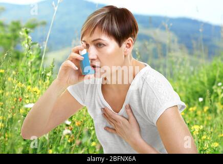 Donna matura che usa l'inalatore per asma all'aperto Foto Stock