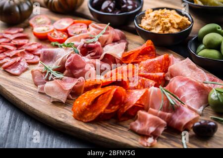 Piatto di antipasti con un misto di salame, prosciutto, chorizo, peperoni, pomodori e olive Foto Stock