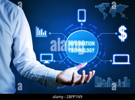Uomo d'affari che detiene icone virtuali e tecnologia di INFORMAZIONE testuale su sfondo scuro Foto Stock