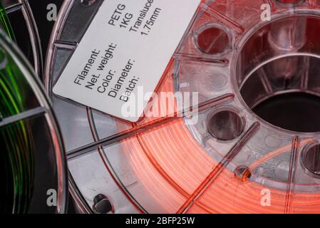Bobine di filamento per stampa 3d da 1,75 mm, verde traslucido e arancione traslucido, sfondo scuro Foto Stock