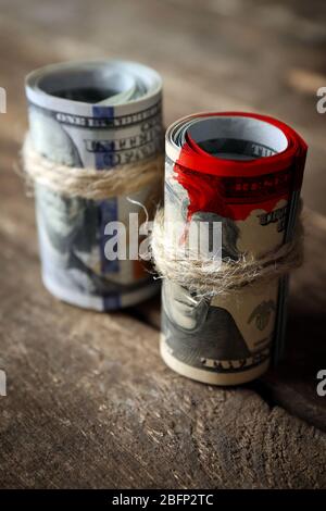 I dollari rotolano con macchie di sangue su sfondo di legno Foto Stock