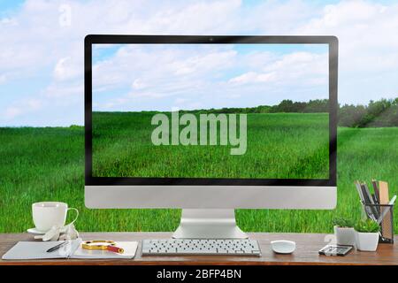 Immagine concettuale di uno spazio di lavoro e di un desktop con campo verde e cielo blu Foto Stock