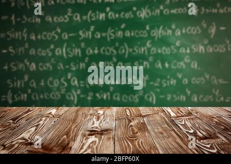Tavolo in legno su sfondo lavagna. Concetto scolastico. Foto Stock