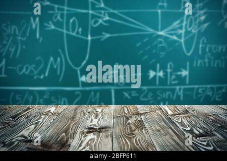 Tavolo in legno su sfondo lavagna. Concetto scolastico. Foto Stock