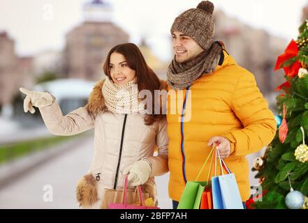 Bella coppia con borse colorate sullo sfondo della città sfocata strada. Vacanze invernali e natale concetto di shopping. Foto Stock