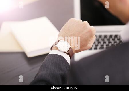 Imprenditore controllando il tempo sul suo orologio da polso, close up Foto Stock