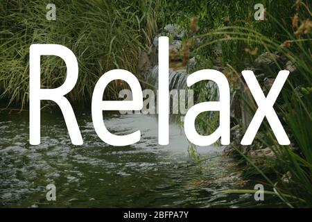 Parola RELAX e piccola cascata sullo sfondo. Foto Stock