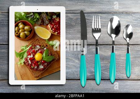 Appuntamenti e tablet. Foto del cibo sullo schermo del tablet. Foto Stock