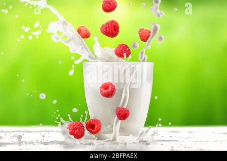 Versare il latte in vetro sul tavolo con fondo verde Foto Stock