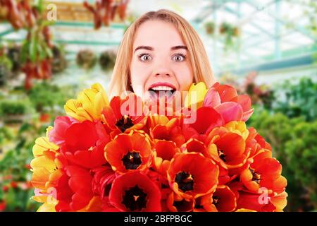 Giovane donna con bel bouquet di tulipani sullo sfondo negozio di fiori Foto Stock