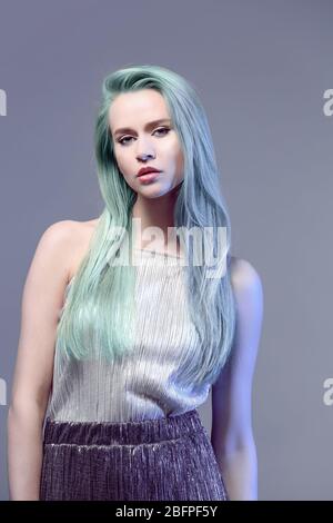 Idee di acconciatura alla moda. Giovane donna con colore menta capelli su sfondo grigio Foto Stock