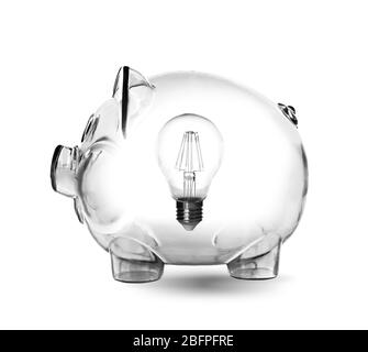 Piggy bank con lampadina su sfondo bianco. Aumento dei costi dell'elettricità Foto Stock