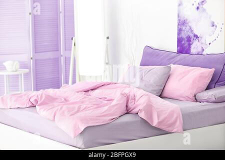 Il colore lilla è accentuato negli interni moderni. Letto comodo in camera luminosa Foto Stock