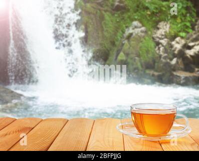 Tazza di tè e cascata sullo sfondo Foto Stock