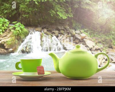 Tazza di tè con pentola e cascata sullo sfondo Foto Stock