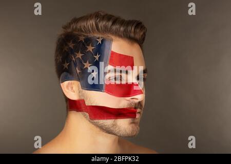 Concetto patriottico. Giovane uomo con faccia dipinta come bandiera americana su sfondo colorato Foto Stock