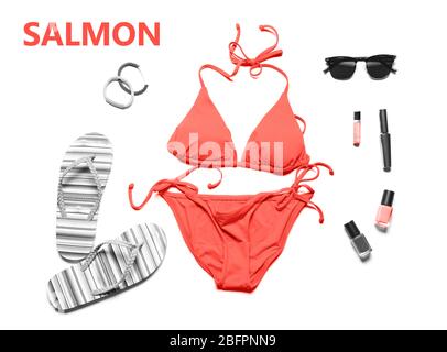 Set di colori salmone con bikini e accessori da spiaggia su sfondo bianco Foto Stock