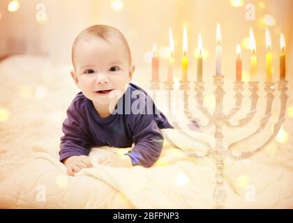 Bambino piccolo su sfondo festivo sfocato luci. Il primo Hanukkah del bambino Foto Stock