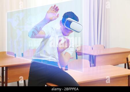 Ragazzo con occhiali per realtà virtuale in classe. Concetto di scuola e tecnologia moderna Foto Stock