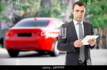 Agente assicurativo che utilizza tablet e auto in background Foto Stock