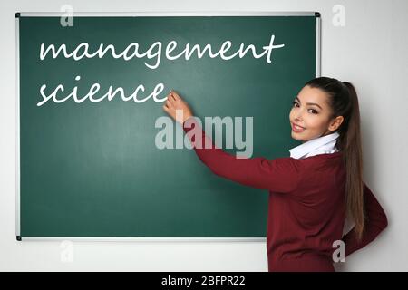 Concetto di scienza di gestione. Giovane donna vicino a lavagna in classe Foto Stock
