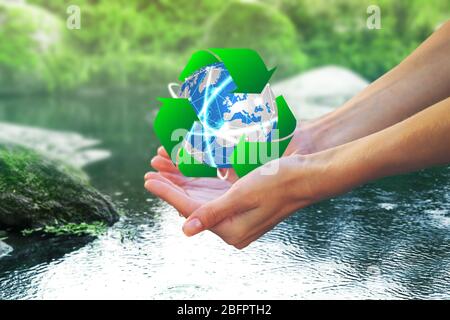 Donna che tiene il globo e segno di riciclaggio sopra l'acqua, closeup. Ecologia e conservazione dell'ambiente Foto Stock