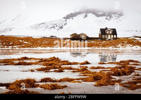 Casa Amtmannshusid ad Arnarstapi sulla penisola di Snaefellsnes in Islanda in una giornata invernale ghiacciata e nevosa nei toni dell'arancio e del bianco Foto Stock