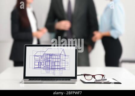 Laptop con disegno di casa e agenti immobiliari sullo sfondo Foto Stock