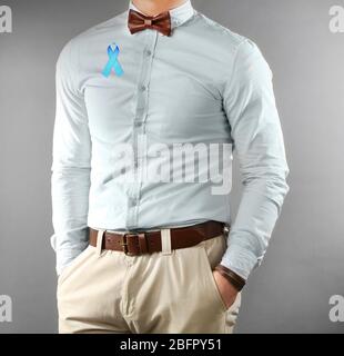 Giovane uomo con nastro blu su sfondo grigio. Concetto di cancro della prostata Foto Stock