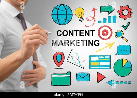 Uomo d'affari che lavora con schermo virtuale su sfondo grigio. Concetto di marketing dei contenuti Foto Stock