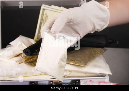 Cocaina e marijuana con pistola in valigia con mano che tiene un pacchetto di cocaina closeup Foto Stock