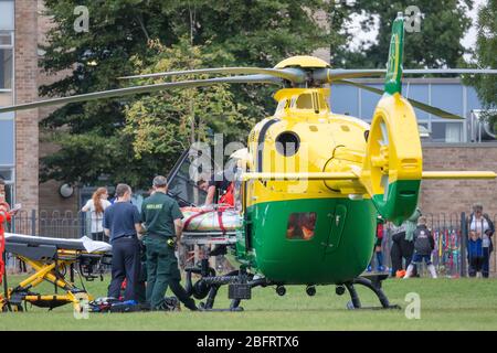 Team di emergenza NHS che consegna il paziente a Hampshire e all'isola di Wight Air Ambulance - Airbus H135 G-HIOW a Basingstoke, Regno Unito Foto Stock