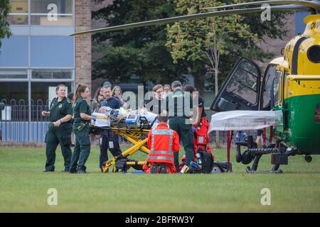 Team di emergenza NHS che consegna il paziente a Hampshire e all'isola di Wight Air Ambulance - Airbus H135 G-HIOW a Basingstoke, Regno Unito Foto Stock