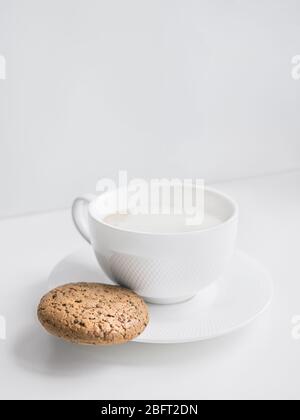 Tazza di caffè Foto ravvicinata con spazio copia caffè fatto in casa con latte in una tazza bianca e biscotti con fiocchi d'avena e patatine di cioccolato sul tavolo Foto Stock