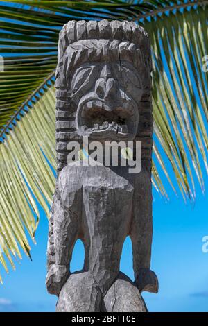 Figura Guardiana Tiki di fronte alla foglia di palma, pu'uhonua o Honaunau National Historical Park, Big Island, Hawaii, USA Foto Stock