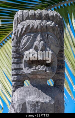 Figura Guardiana Tiki di fronte alla foglia di palma, pu'uhonua o Honaunau National Historical Park, Big Island, Hawaii, USA Foto Stock