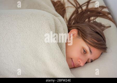 Donna a letto coperta fino al viso Foto Stock