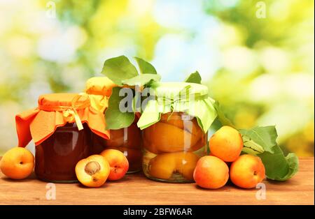 albicocche in scatola in un vaso e albicocche dolci su tavola di legno su sfondo verde Foto Stock