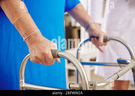Immagine ravvicinata della donna anziana che usa il camminatore quando si muove in casa Foto Stock