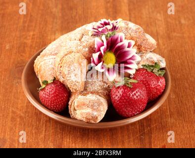 Bagel freschi con fragola nel piatto su sfondo di legno primo piano Foto Stock