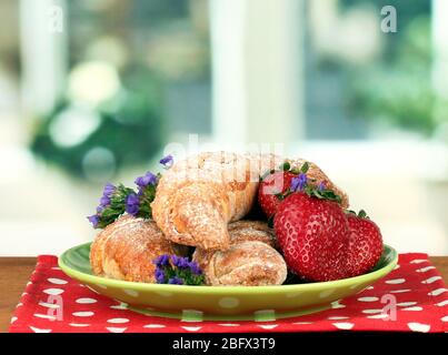 Bagel freschi con fragola nel piatto sul tavolo Foto Stock