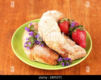 Bagel freschi con fragola nel piatto su sfondo di legno primo piano Foto Stock