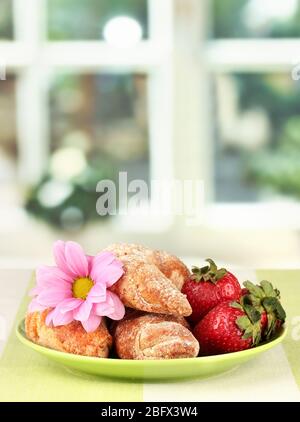 Bagel freschi con fragola nel piatto sul tavolo Foto Stock