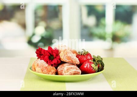 Bagel freschi con fragola nel piatto sul tavolo Foto Stock