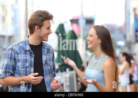 Due amici felici che si incontrano e parlano per strada in una città Foto Stock